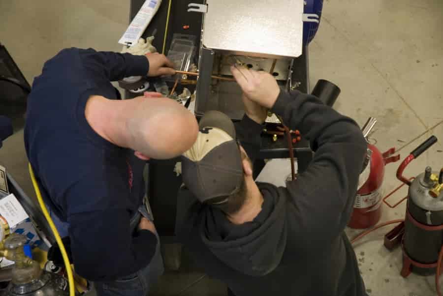 HVAC student practicing on unit overseen by an experienced technician
