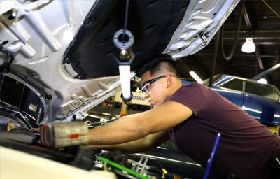 Auto mechanic student working on car