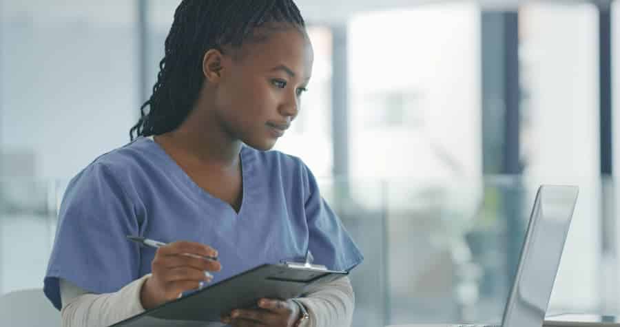 A health information technician looking at medical records and making notes 