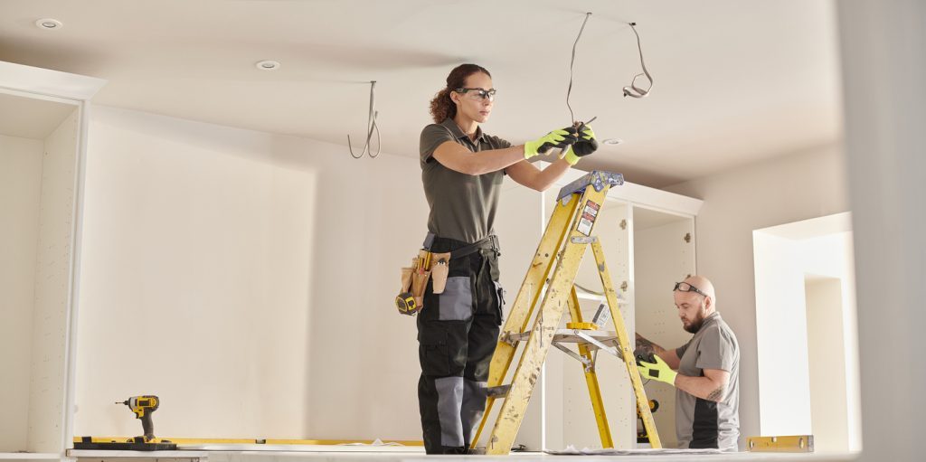 Two electricians install wiring inside room