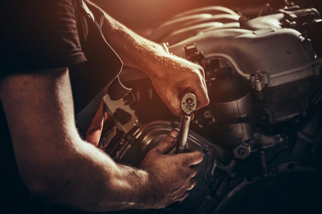 Diesel mechanic loosens part with specialized wrench