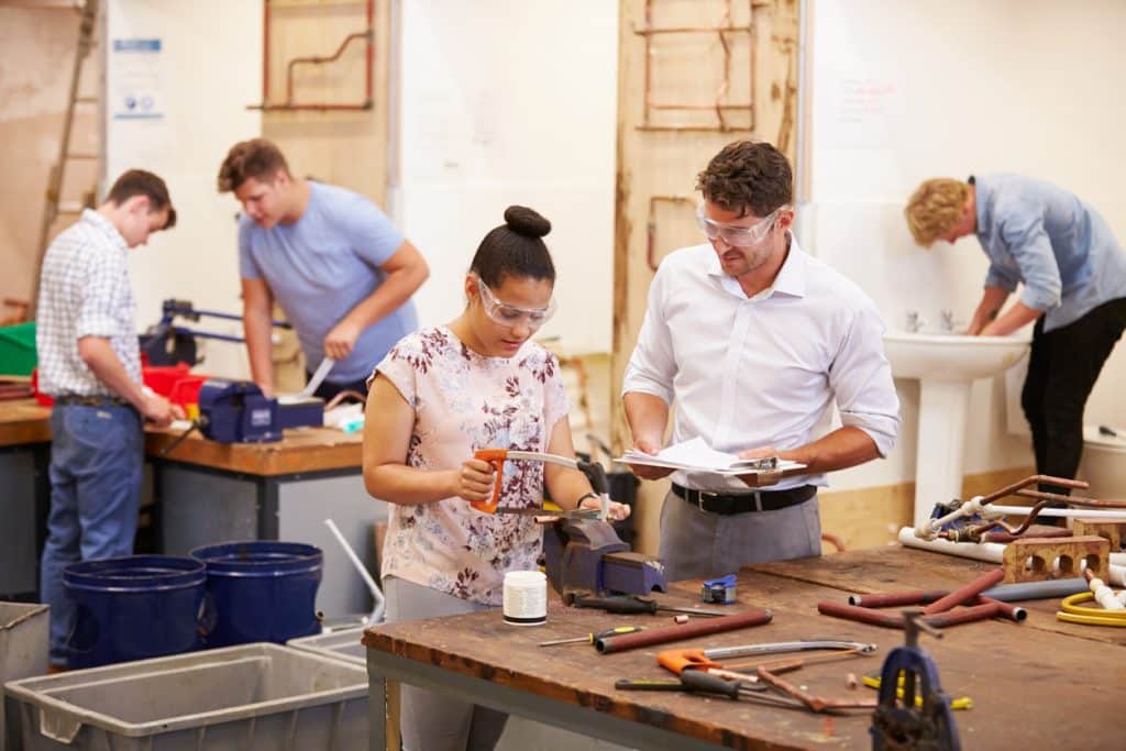 Instructor assists student using tools at plumbing school
