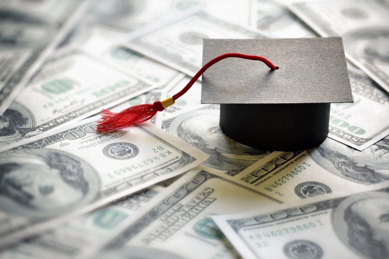 Miniature graduation cap on top of dollar bills