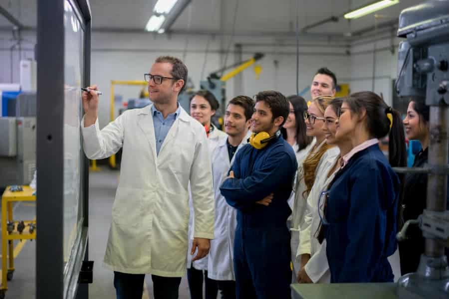 Trade school students with teacher writing on whiteboard