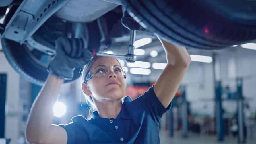 Mechanic wearing safety glasses working on lifted vehicle