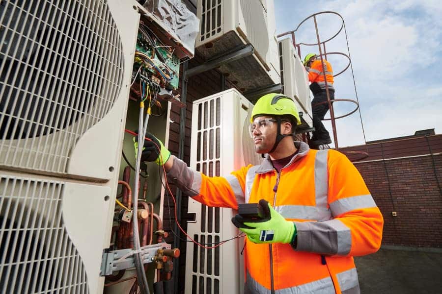 Worker in orange vest repairing air conditioning unit