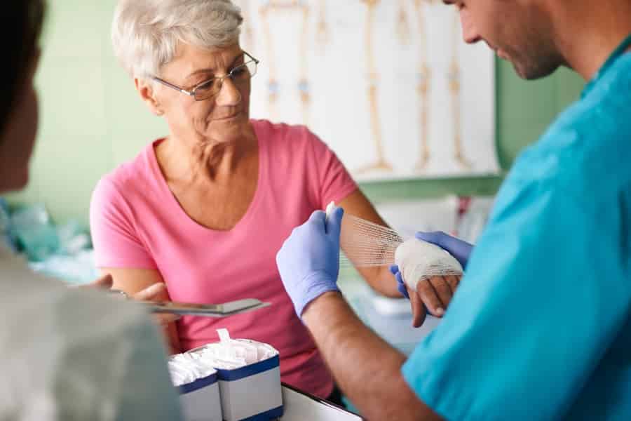 Medical assistant putting bandage on patient’s hand